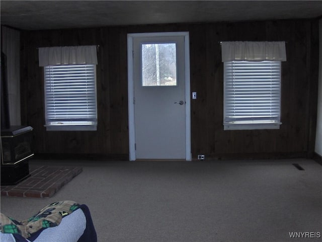 carpeted foyer featuring a wealth of natural light and a wood stove