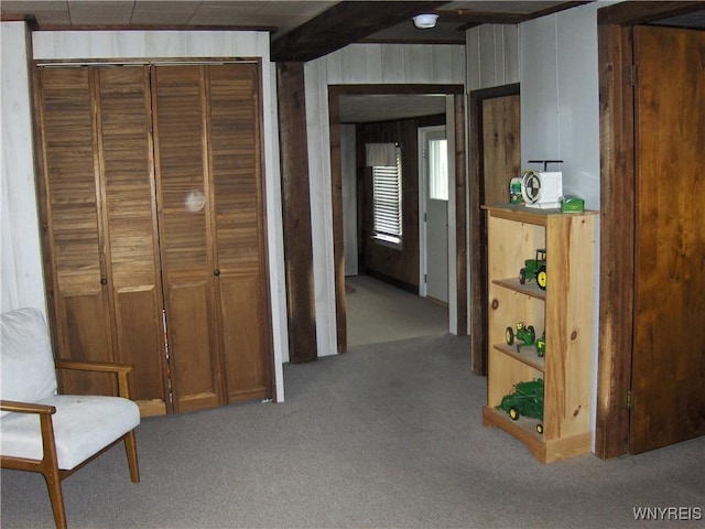 hall with beam ceiling, wooden walls, and carpet floors