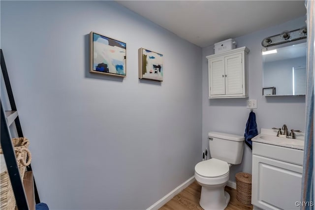 bathroom featuring toilet, vanity, baseboards, and wood finished floors