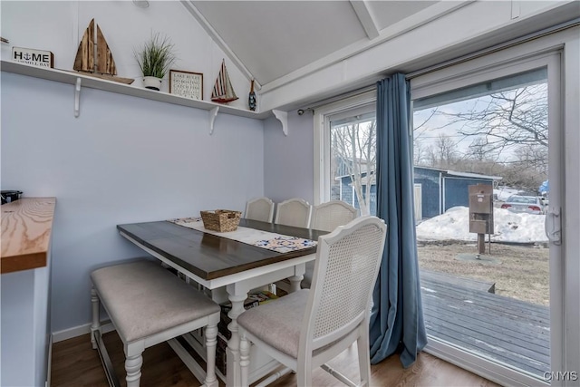 dining space featuring baseboards, lofted ceiling, and wood finished floors