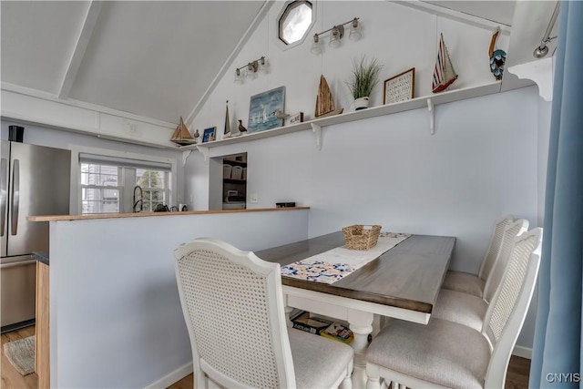 dining space featuring vaulted ceiling and wood finished floors