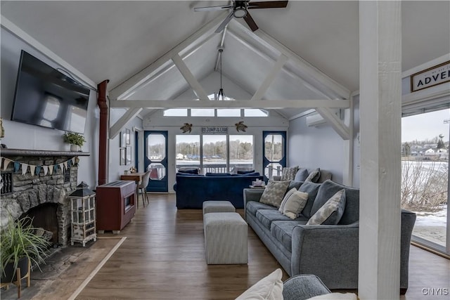 living area with wood finished floors, ceiling fan, a fireplace, and vaulted ceiling