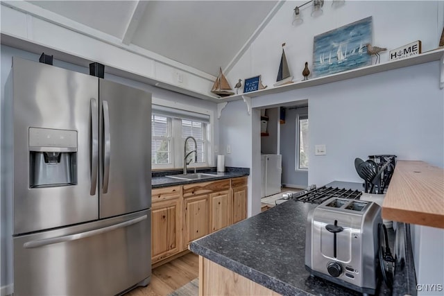 kitchen with washer / clothes dryer, stainless steel fridge with ice dispenser, a sink, vaulted ceiling, and light wood-style floors