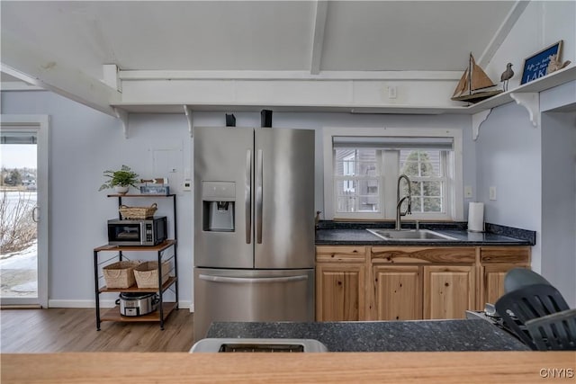 kitchen with wood finished floors, open shelves, a sink, appliances with stainless steel finishes, and dark countertops