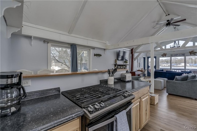 kitchen featuring range with gas stovetop, a ceiling fan, lofted ceiling with beams, dark countertops, and open floor plan