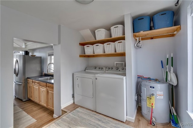 laundry area with light wood finished floors, laundry area, water heater, a sink, and washing machine and dryer