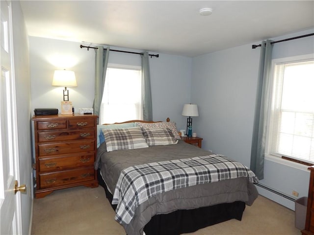 bedroom featuring a baseboard heating unit, multiple windows, and light colored carpet