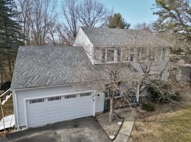 view of front facade with a garage and roof with shingles