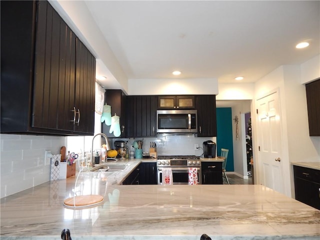 kitchen featuring a sink, light stone counters, backsplash, recessed lighting, and stainless steel appliances