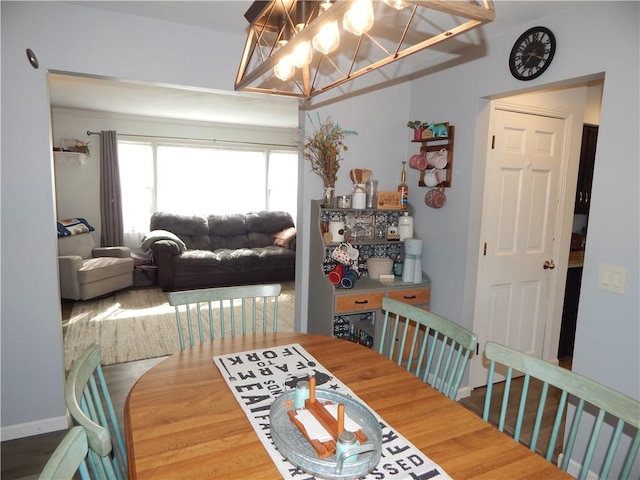 dining area with baseboards, a notable chandelier, and wood finished floors