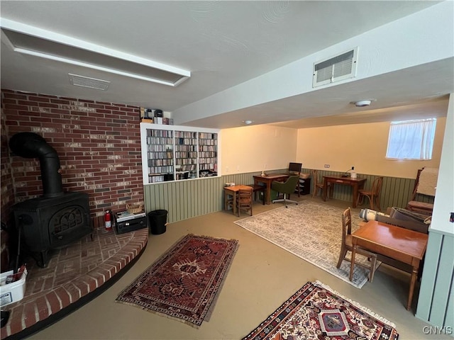 interior space featuring visible vents, brick wall, finished concrete floors, and a wood stove