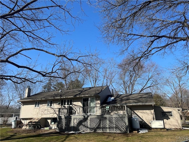 exterior space featuring a front lawn, a chimney, and a wooden deck