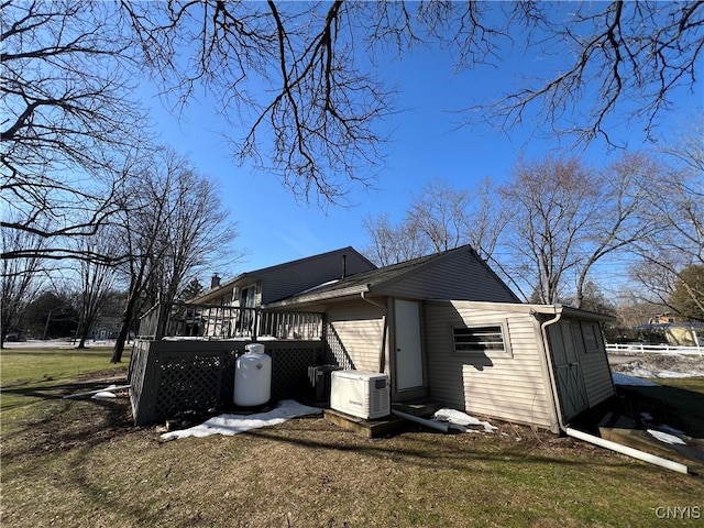 exterior space featuring ac unit, central air condition unit, an outbuilding, a lawn, and a wooden deck