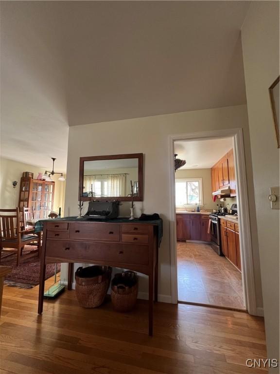 interior space featuring light wood finished floors, brown cabinets, stainless steel range with gas cooktop, and under cabinet range hood