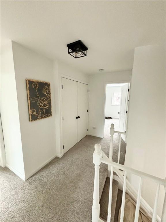 hallway featuring baseboards and light colored carpet