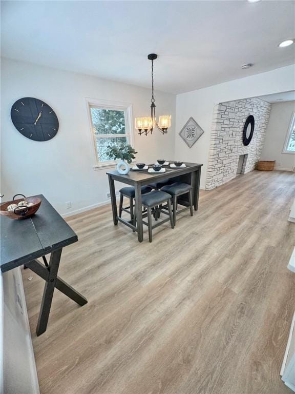 dining space with light wood finished floors, a chandelier, and baseboards