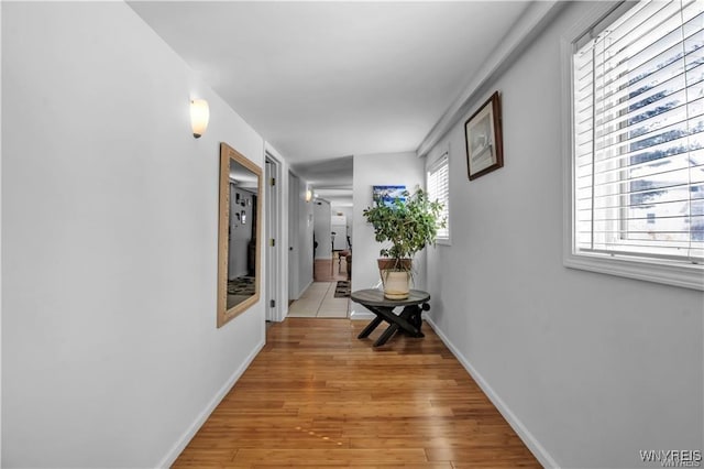 corridor with baseboards and light wood-style flooring