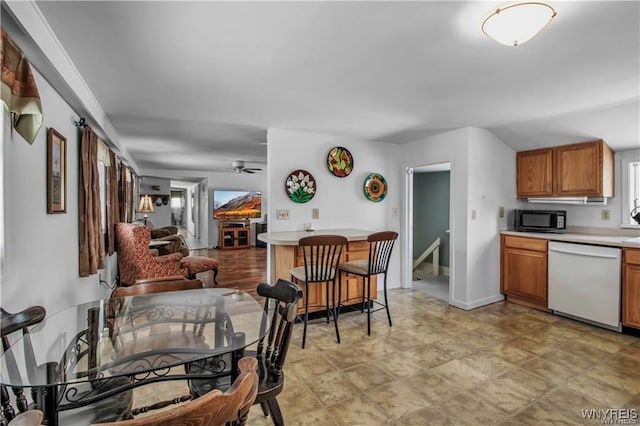 kitchen with black microwave, ceiling fan, dishwasher, light countertops, and brown cabinetry