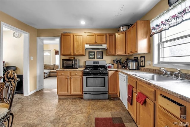 kitchen with a sink, light countertops, under cabinet range hood, dishwasher, and gas range