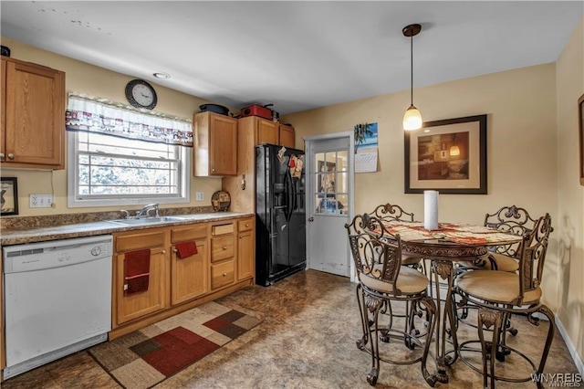 kitchen with pendant lighting, black fridge, white dishwasher, tile patterned floors, and a sink