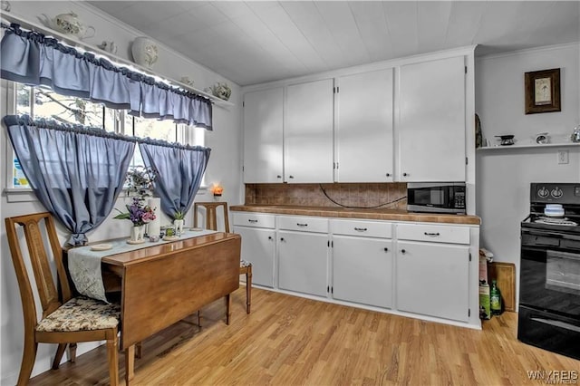 kitchen with light wood-style flooring, decorative backsplash, black electric range, white cabinetry, and stainless steel microwave