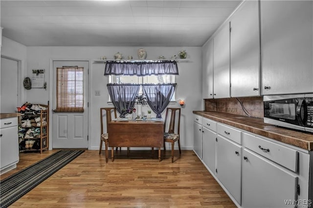 kitchen featuring stainless steel microwave, light wood-style floors, tasteful backsplash, and a wealth of natural light