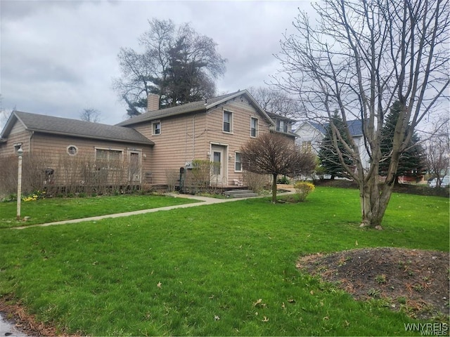 rear view of house featuring a chimney and a yard