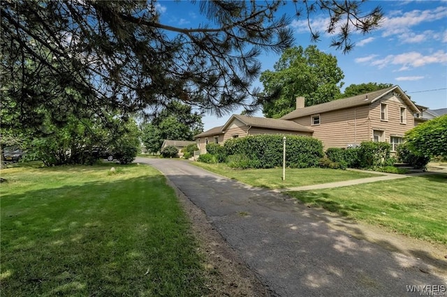 view of side of home with a yard and a chimney