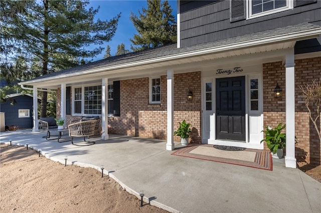 property entrance featuring brick siding and covered porch