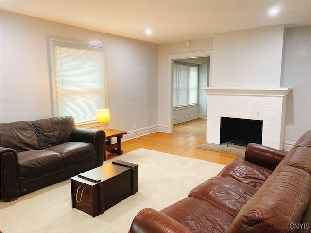 living area featuring recessed lighting, a brick fireplace, baseboards, and wood finished floors