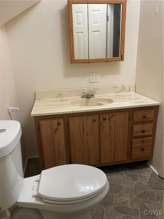 bathroom with stone finish flooring, toilet, and vanity