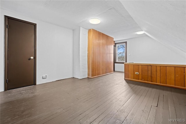 additional living space with hardwood / wood-style floors and vaulted ceiling