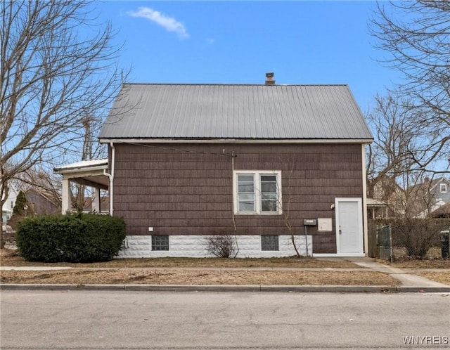 view of home's exterior with metal roof and fence