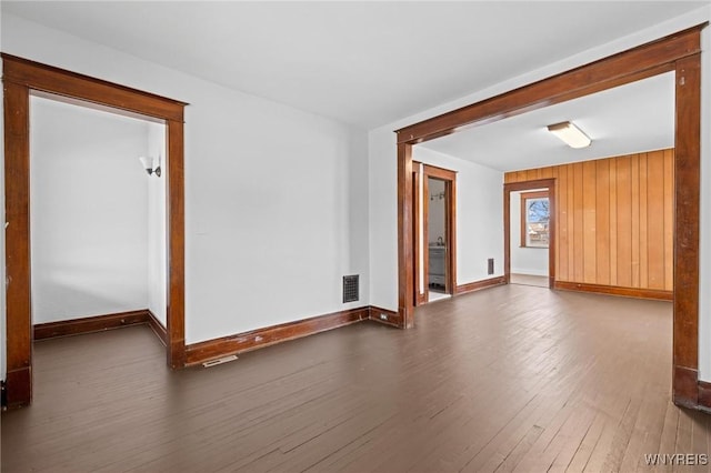 spare room with visible vents, baseboards, and wood finished floors