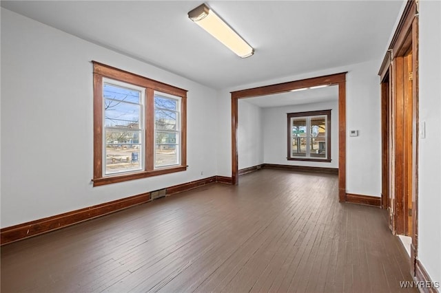 spare room with visible vents, baseboards, and dark wood-style floors