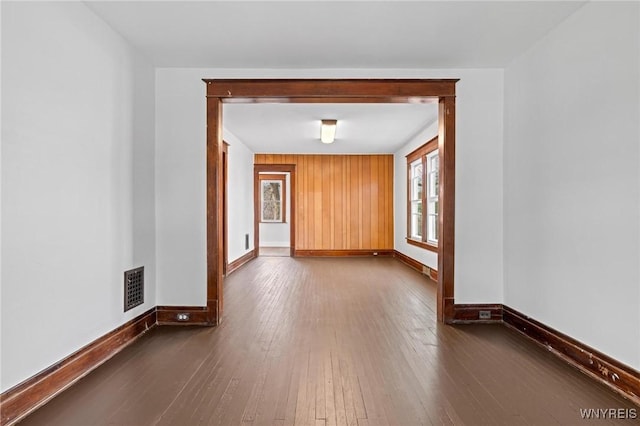 empty room featuring visible vents, baseboards, and dark wood-style floors