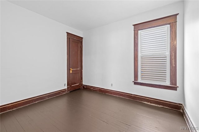 unfurnished room with baseboards and dark wood-style flooring