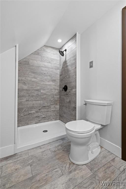 bathroom featuring baseboards, toilet, and a tile shower