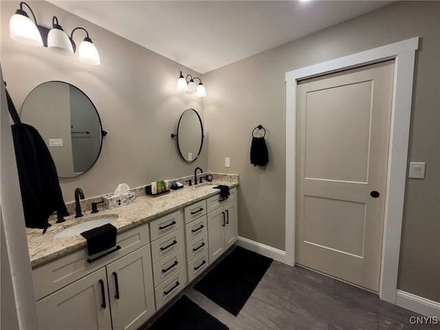 bathroom featuring double vanity, baseboards, and a sink