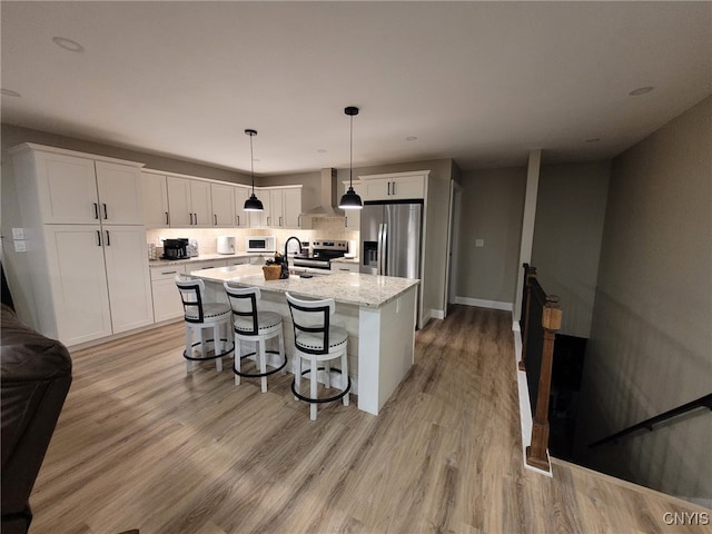 kitchen featuring white cabinetry, light wood-style flooring, wall chimney exhaust hood, and appliances with stainless steel finishes