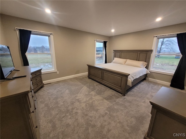 bedroom with multiple windows, light colored carpet, and baseboards