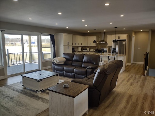 living room featuring light wood finished floors, recessed lighting, and baseboards