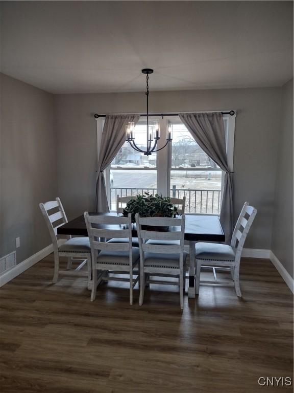 dining area with a chandelier, dark wood-style floors, visible vents, and baseboards