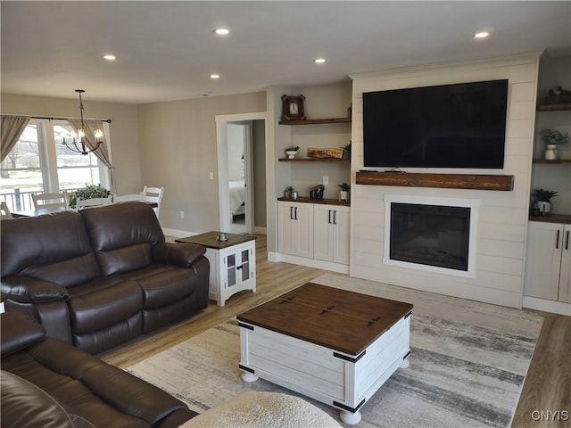 living room with baseboards, an inviting chandelier, recessed lighting, a fireplace, and light wood-type flooring