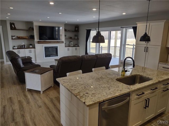 kitchen featuring a sink, dishwasher, open floor plan, and an island with sink