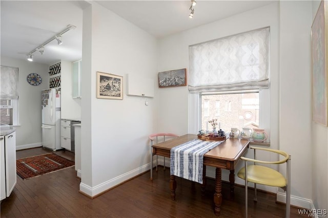 dining space with hardwood / wood-style flooring, baseboards, and track lighting