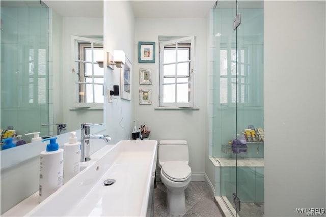 full bath featuring baseboards, toilet, a healthy amount of sunlight, and a shower stall