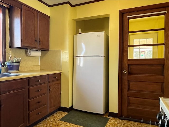 kitchen featuring a sink, baseboards, light countertops, and freestanding refrigerator