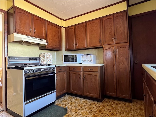 kitchen featuring white microwave, tasteful backsplash, under cabinet range hood, light countertops, and gas stove