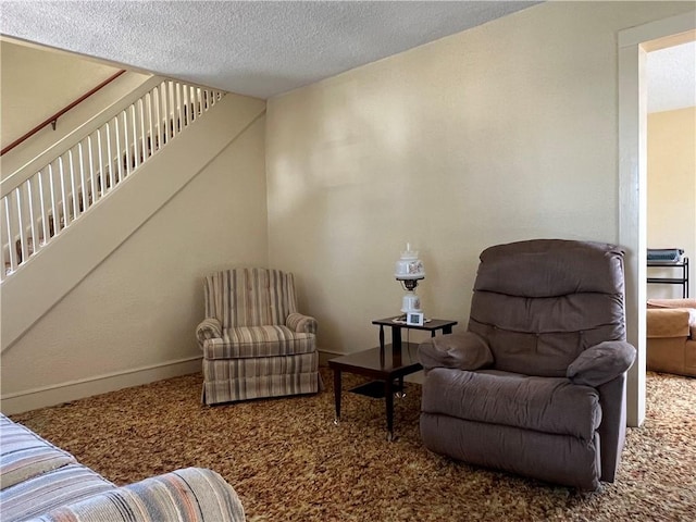 living area with carpet flooring, a textured ceiling, stairs, and baseboards